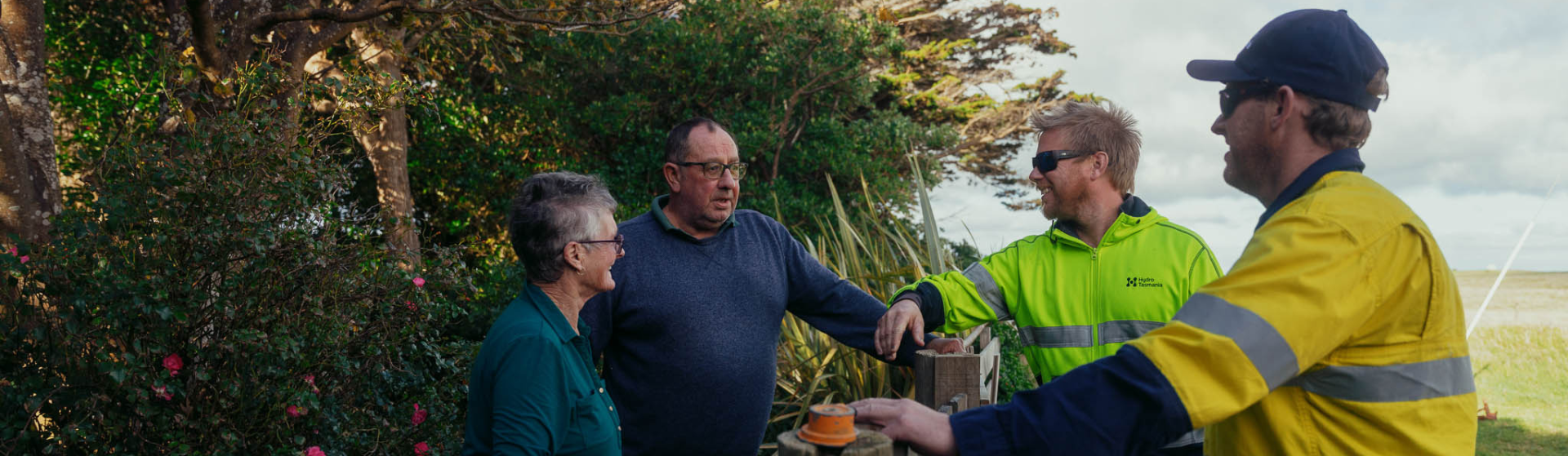 两名水力工人与他们家前花园的两个社区成员交谈