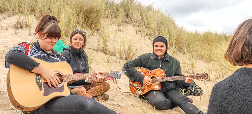 学生和音乐家学习在海滩上弹吉他