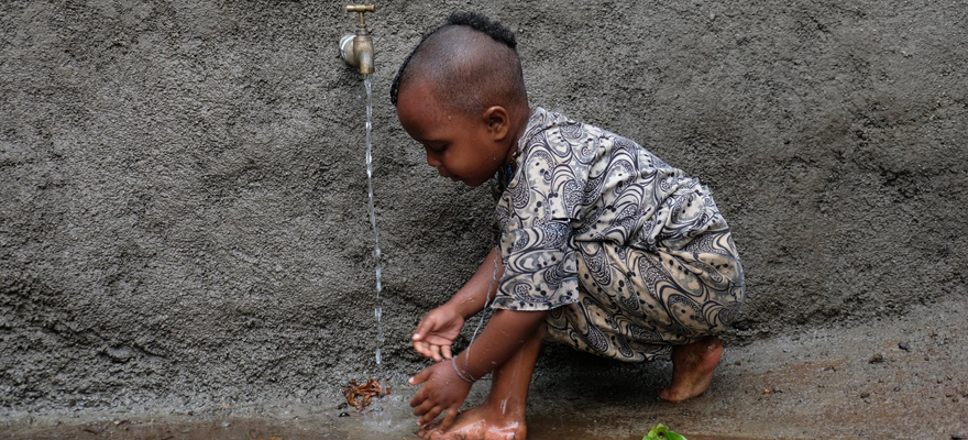 一个小女孩在她的村庄的新井装置前清洁